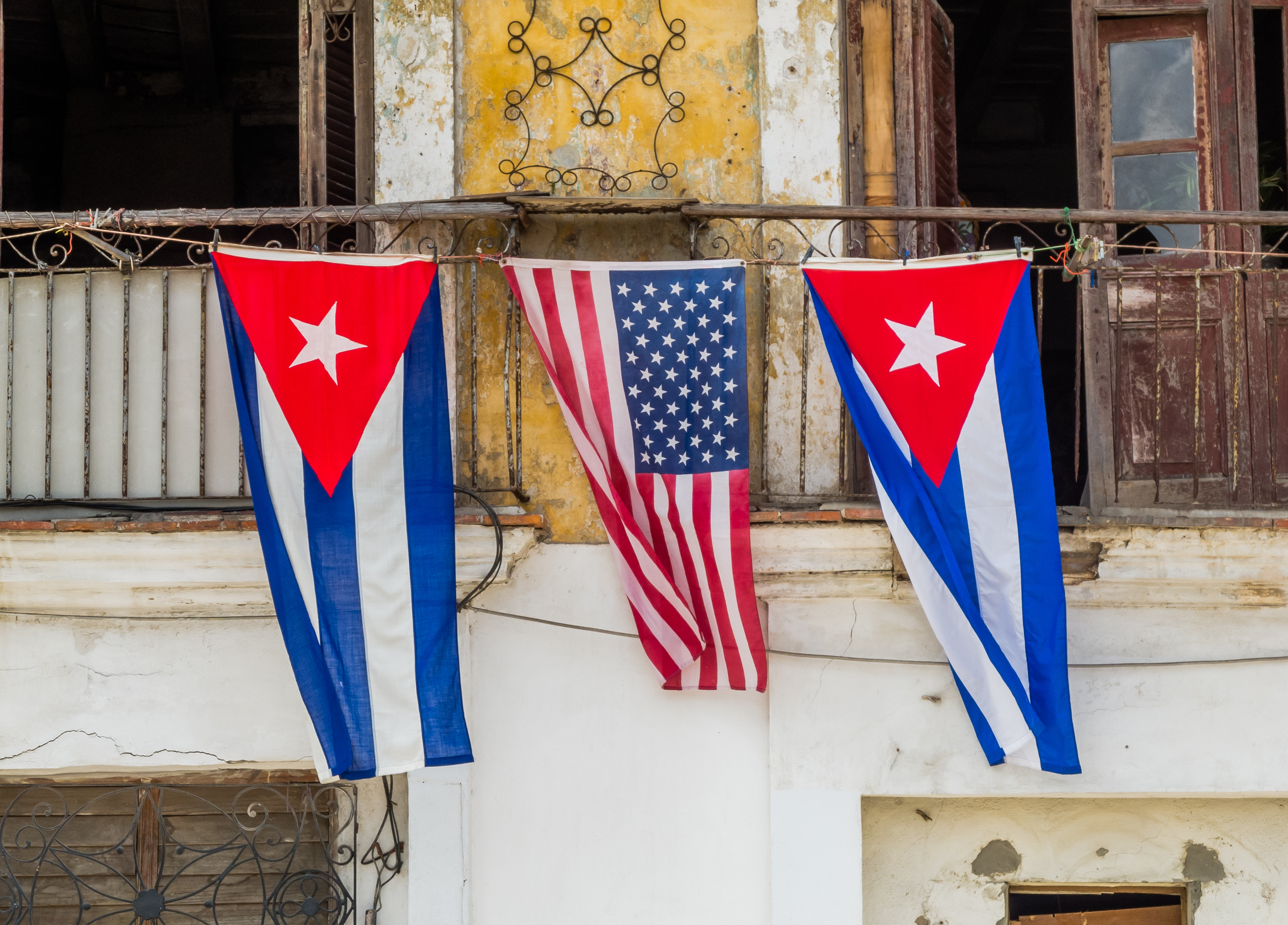 Cuba Terrorism List US Policy Impact blocks normalized ties. An unknown enthusiastic local reacts to President Obama´s visit to Cuba hanging both Cuban and American flags on his balcony.