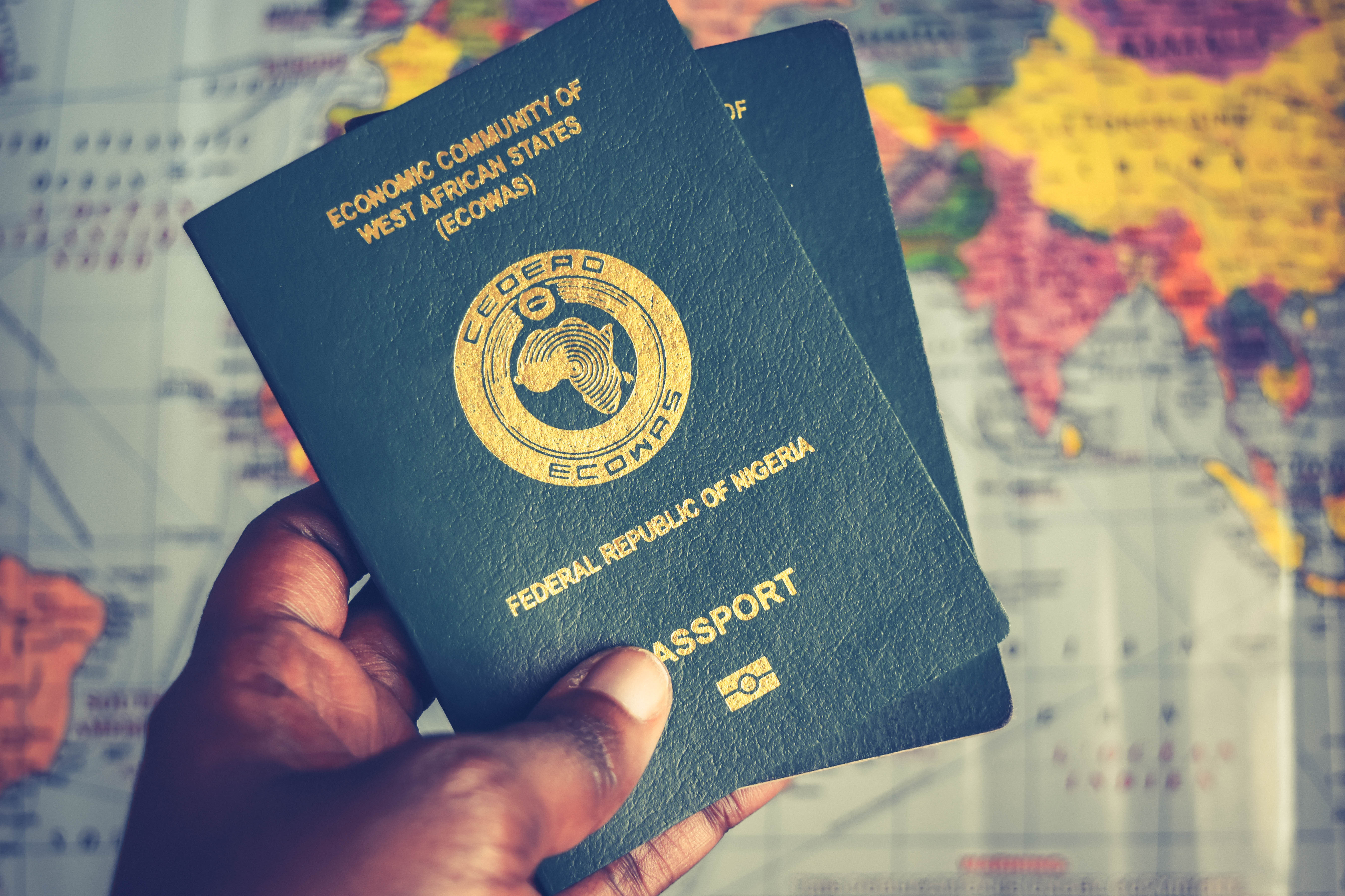 African hand holding ECOWAS and Nigerian passports with Sahel map backdrop symbolizing break from ECOWAS