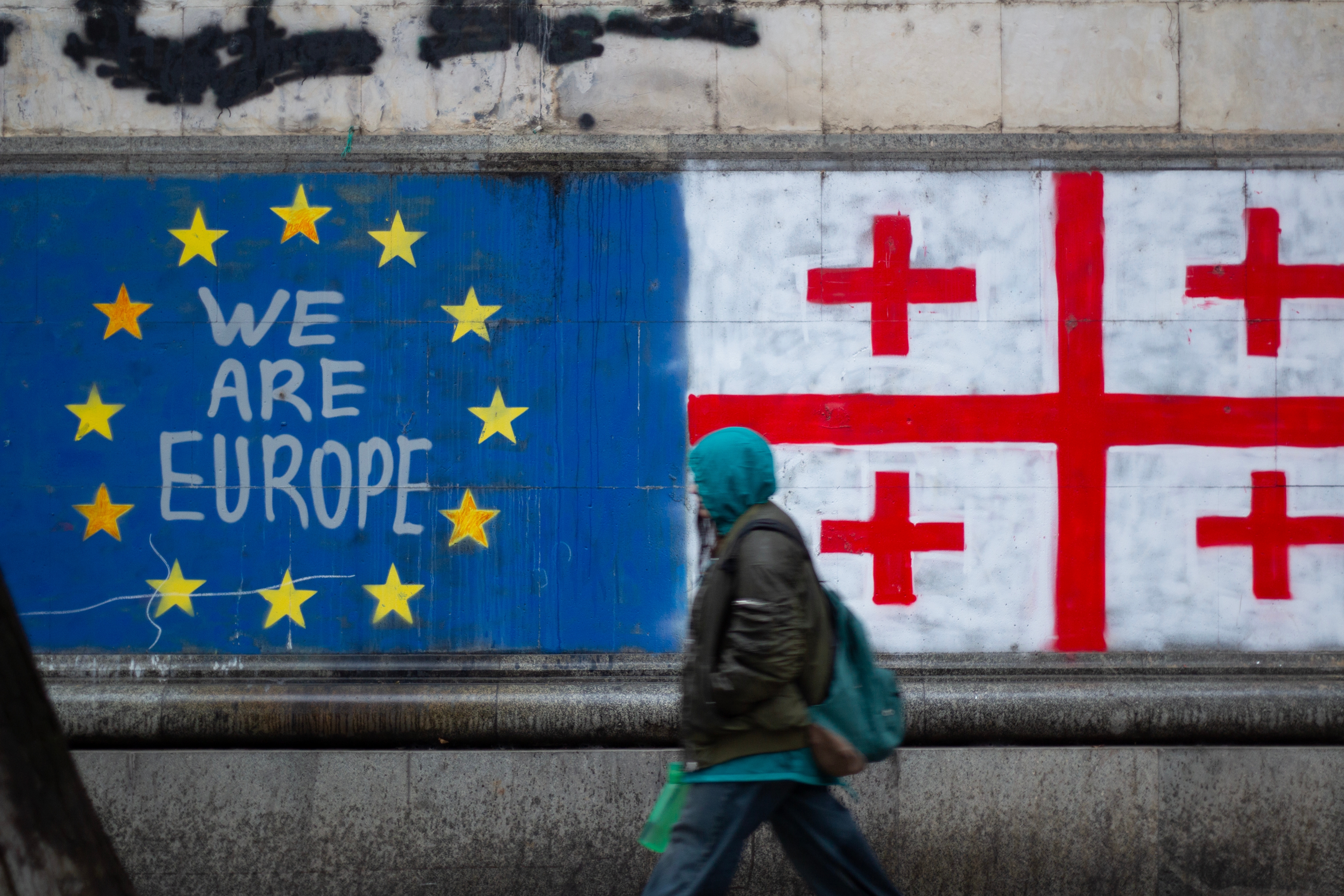 Georgia EU accession protests Tbilisi Georgia November 25 2024 People out of focus near text We are Europe EU and Georgian flag cross yellow star on blue house wall Peaceful protest against result of parliament election