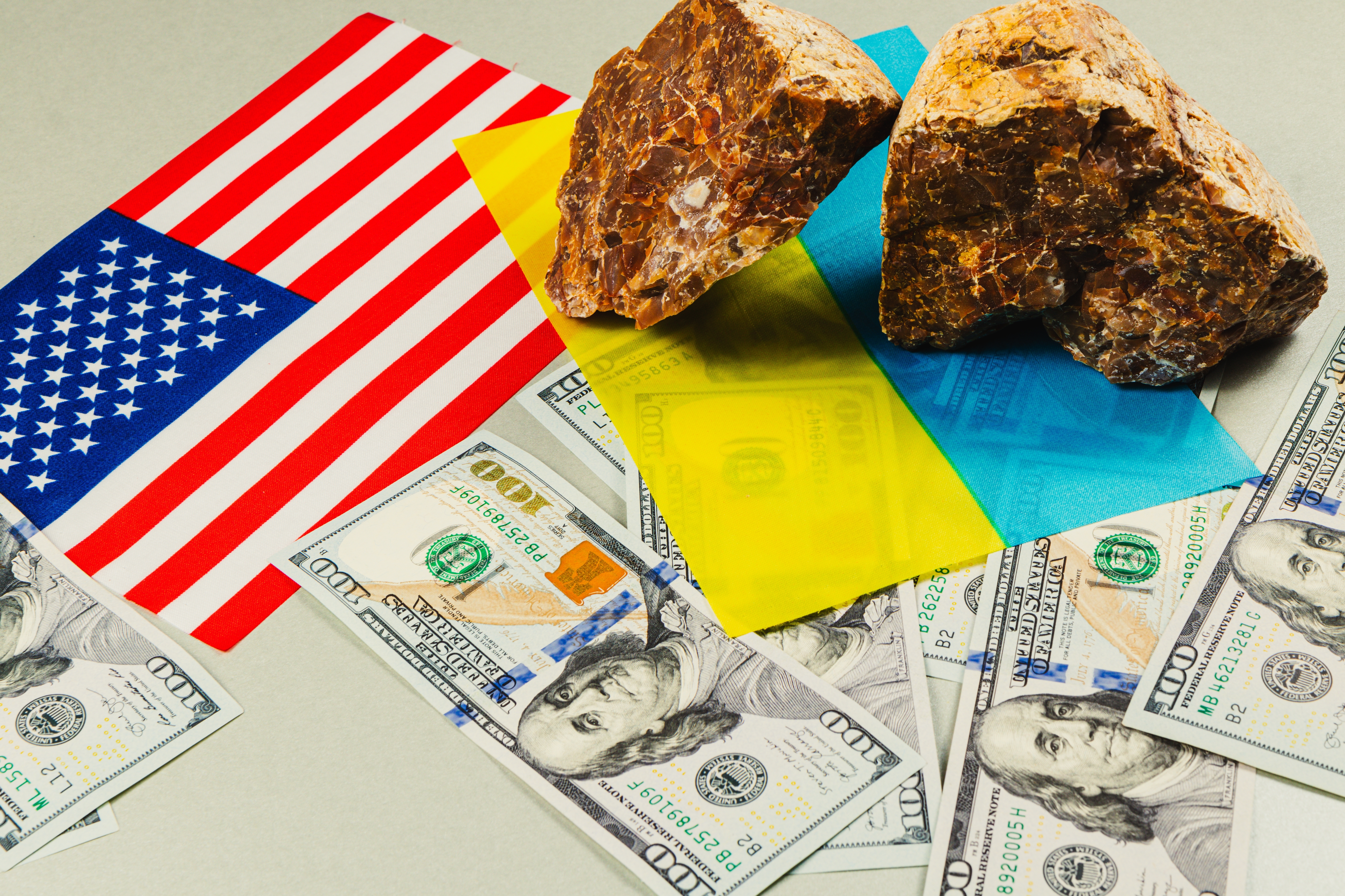 US-Ukraine minerals deal shown with mineral rocks, US currency, and flags of Ukraine and USA highlighting power, resources, and geopolitical interests