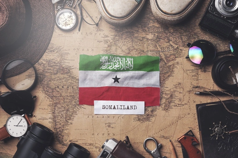 Somaliland Flag Between Traveler's Accessories on Old Vintage Map. Overhead Shot