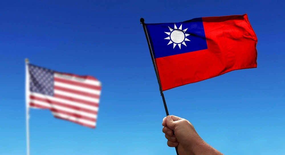 Holding Taiwan flag waving under cloudy sky. Fly in the sky. Deliberately blurry shot of the American flag in the distance