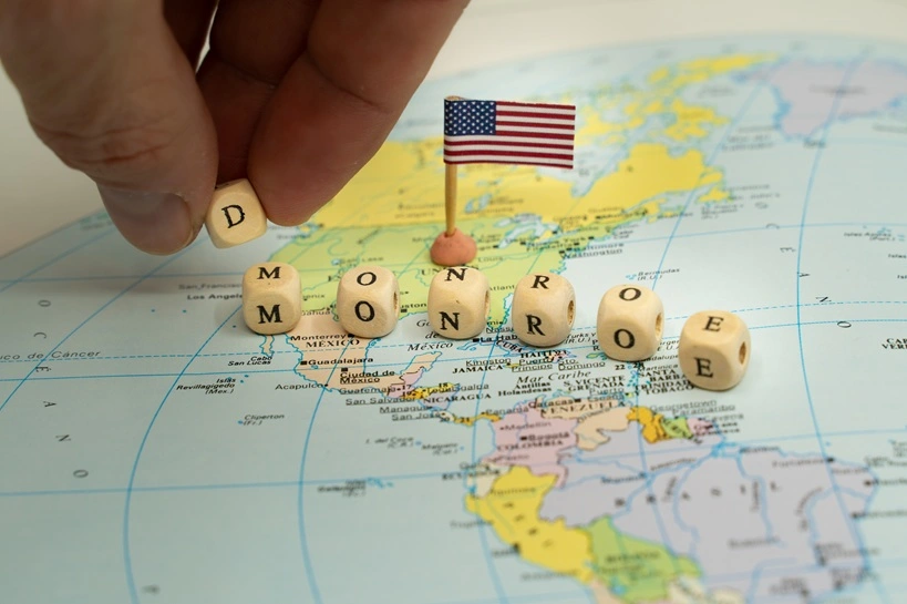 Person's hand changing the word Monroe to Donroe with wooden blocks on a map of the Americas, representing a conceptual shift in United States foreign policy and its doctrine. U.S. Influence. Source: Shutterstock