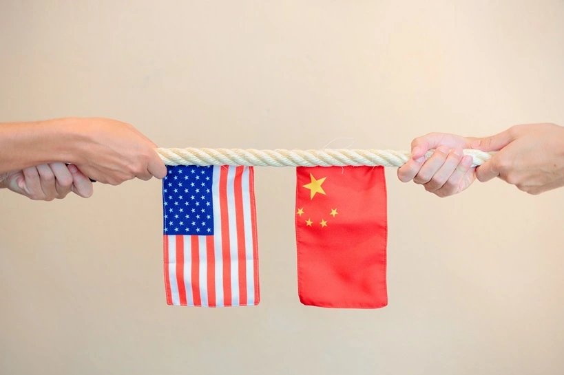 Tug of war with US and China flags on a rope, pulled by hands from both sides, symbolizing trade conflict, tariffs, and the global power struggle. Source: Shutterstock